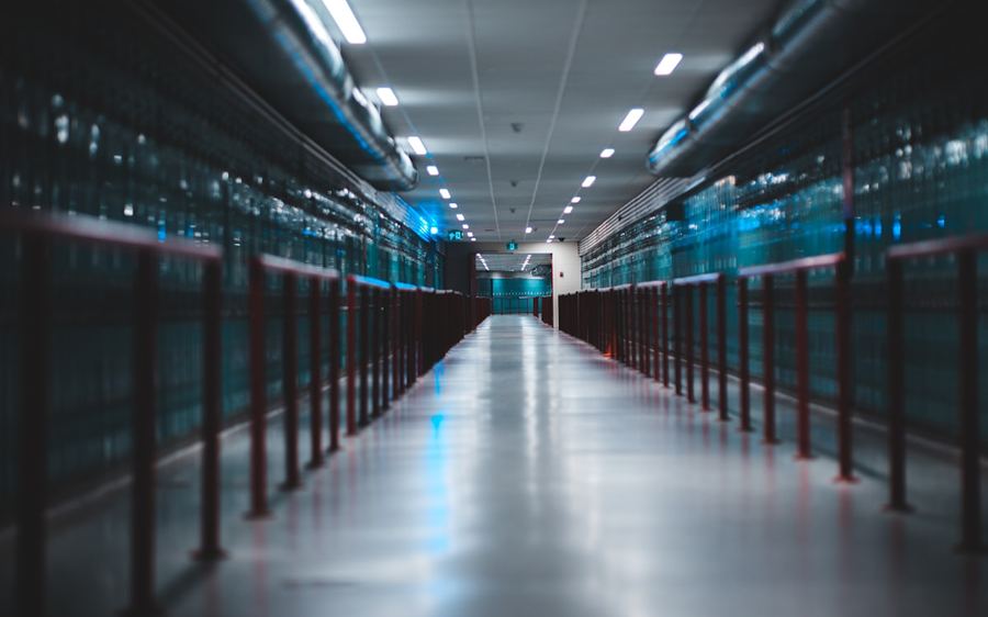 A data-centre corridor lit blue, racks receding to a vanishing point