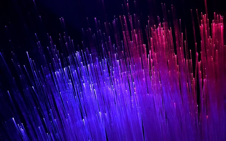 Optical fibre strands glowing violet and magenta against black